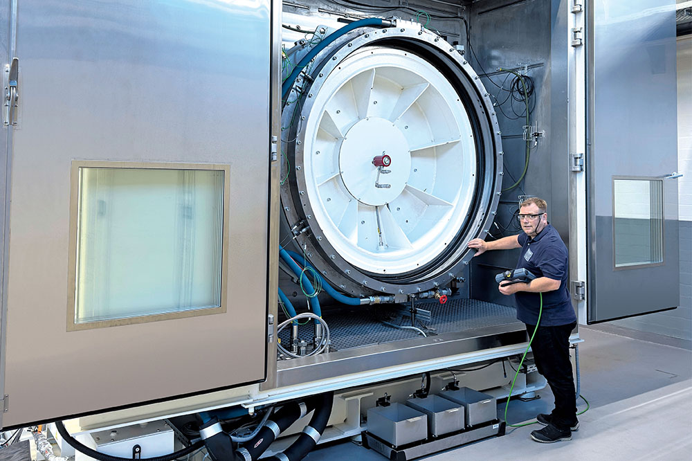 A man standing in front of a large machine and is checking its functions.